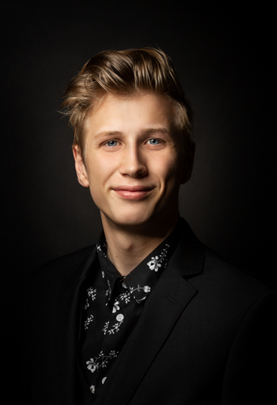 A blonde male in suit smiling at the camera, whom is the creator of Archivian